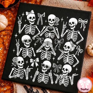 May include: A black canvas print featuring a white graphic pattern of nine skeletons in various poses, including making hand gestures, wearing bows, sunglasses, and heart-shaped glasses, accented with small star and ribbon illustrations.