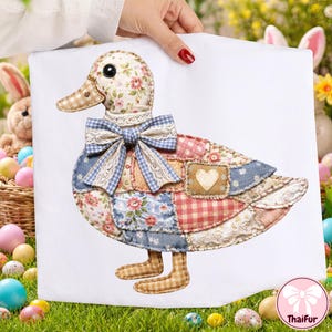 May include: A patchwork duck decoration with a floral head, a gingham beak, and a blue and white bow. The duck's body is made of various fabric patches, including floral, gingham, and solid patterns. A heart-shaped patch is sewn on the body.