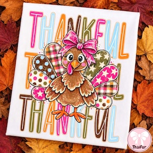 May include: A white t-shirt featuring a brown cartoon turkey with a bright pink bow on its head. The turkey has colorful patterned feathers with polka dots, plaid, and stars. The word THANKFUL is printed in large, multi-colored outlined letters.