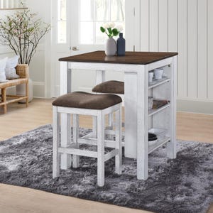 May include: A white and brown square dining table with two matching stools. The table has a dark brown top and white legs. The stools have brown cushioned seats. The table has built-in shelving for storage. The set is on a gray rug.