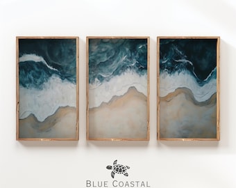 May include: Three framed abstract paintings depicting a blue ocean with white waves crashing on a sandy beach. The paintings are in wooden frames and are arranged in a row.
