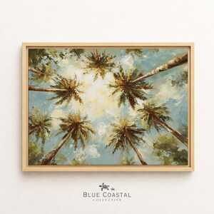 Puede incluir: Un cuadro rectangular enmarcado que muestra una vista en contrapicado de palmeras que se extienden hacia un cielo brillante y nublado. La obra presenta pinceladas visibles en tonos verde, marrón, blanco y azul claro, con un marco de madera clara.