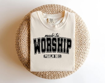 May include: A beige t-shirt with black text that reads "made to worship" and "PSALM 95:1".