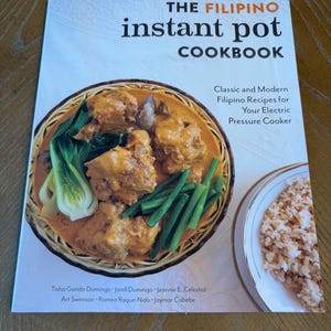 May include: A cookbook titled "The Filipino Instant Pot Cookbook" with a photo of Filipino food. The cover features a dish with meat, vegetables, and rice. The book's subtitle reads "Classic and Modern Filipino Recipes for Your Electric Pressure Cooker."