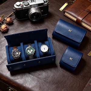 Peut inclure: Un étui à montres en cuir bleu marine contenant trois montres-bracelets, accompagné d'un étui moyen assorti avec les initiales dorées RT et d'un petit étui pour une montre avec les initiales dorées BC, tous dotés d'une doublure bleue douce.