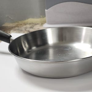 May include: A silver frying pan with a black handle. The pan is empty and has a shiny surface.