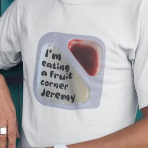 Könnte beinhalten: Ein weißes T-Shirt mit einem Aufdruck eines Plastikbehälters mit dem Text "I'm eating a fruit corner Jeremy".