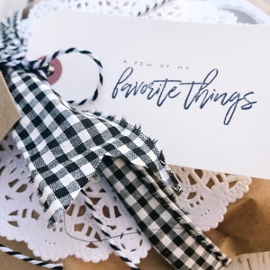 May include: A gift wrapped in brown paper with a white doily, black and white checkered ribbon, and a white tag that says "A Few of My Favorite Things".