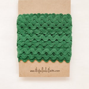 May include: A roll of green wavy trim on a brown paper card with the website www.thepolkadotbarn.com printed on it.