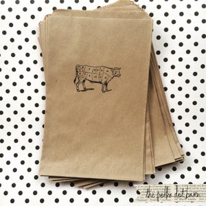 May include: A stack of brown paper bags with a black and white diagram of a cow with numbered cuts of meat. The text "the polka dot barn" is visible on the bottom of the image.