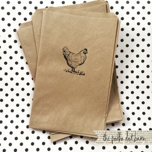May include: A stack of brown paper bags with a black and white illustration of a chicken on the front. The bags are on a white background with black polka dots.