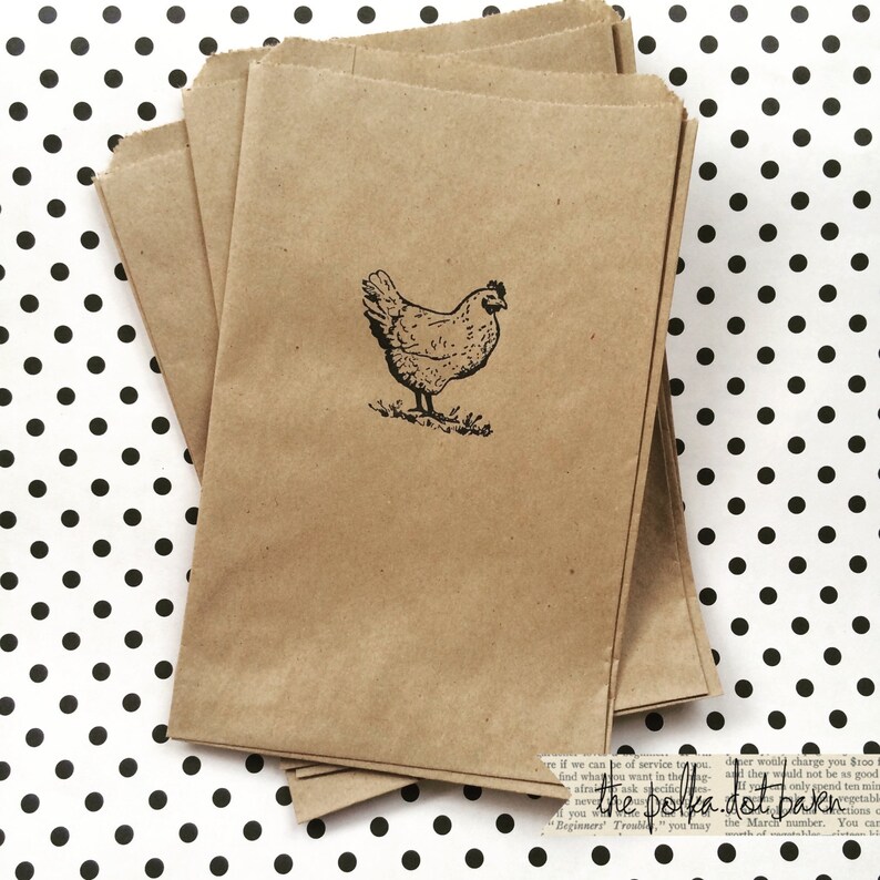 May include: A stack of brown paper bags with a black and white illustration of a chicken on the front. The bags are on a white background with black polka dots.