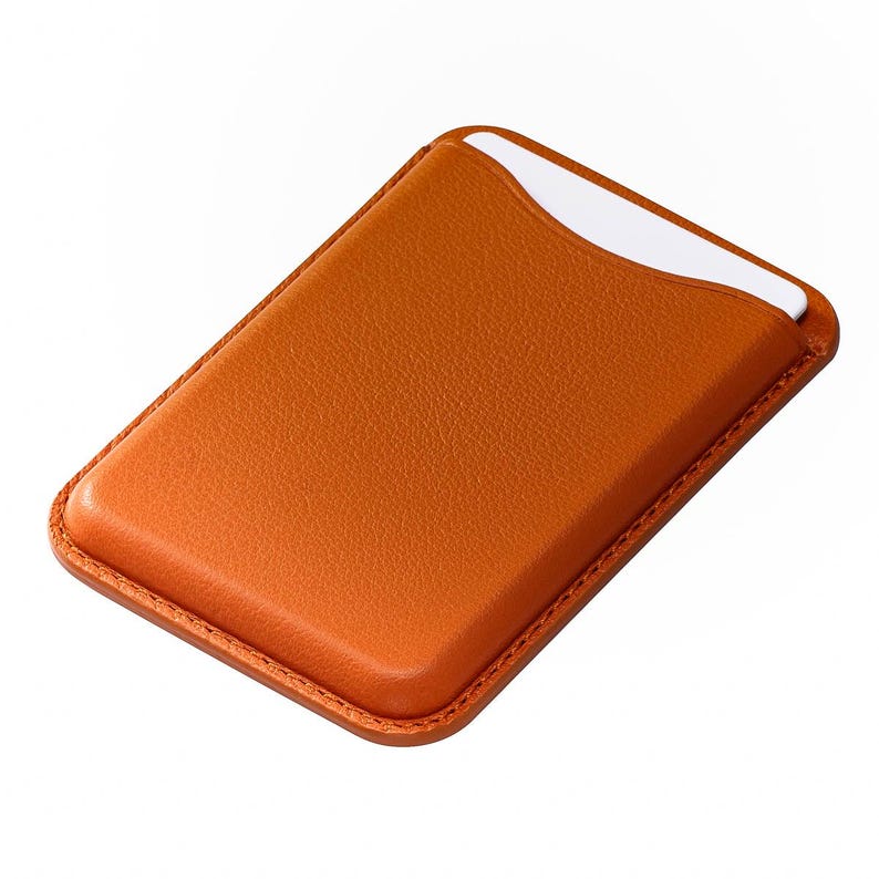 May include: A rectangular, orange leather card holder with a white card partially visible in the top slot. The card holder has a stitched border and a smooth, textured surface. The design is simple and functional.