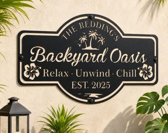Puede incluir: Un letrero de metal negro con un borde decorativo que presenta el texto "THE REDDING'S Backyard Oasis", "Relax · Unwind · Chill" y "EST. 2025". El diseño incluye recortes de tres palmeras y dos flores de hibisco en los lados.
