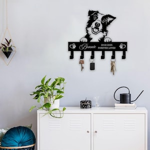 May include: Black metal key holder featuring a silhouette of a Border Collie dog. The holder has six hooks and a personalised inscription that reads "Bonnie 2018-2025 Forever Loved".