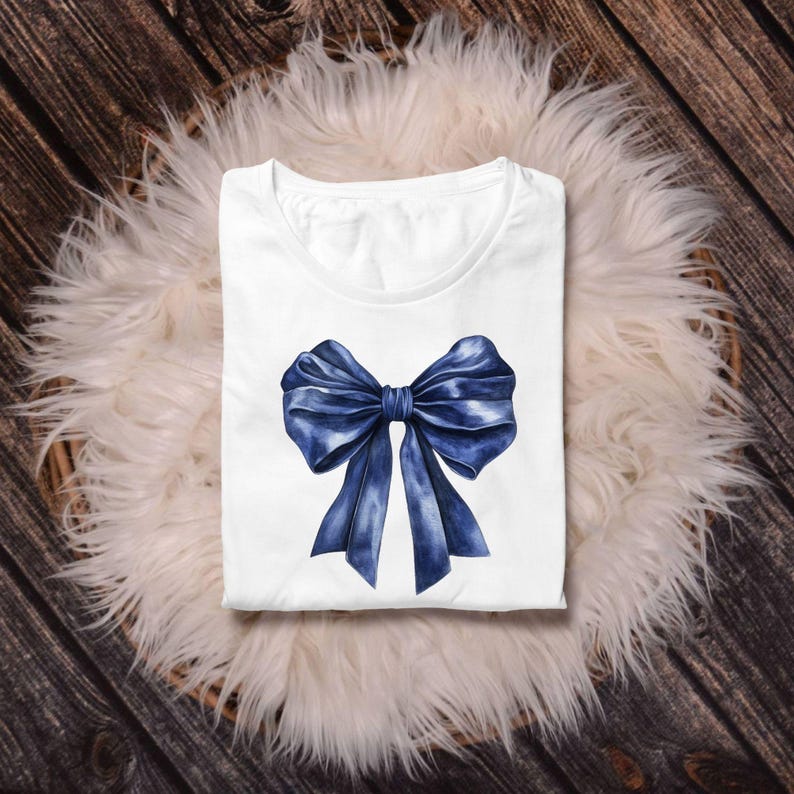 May include: A white t-shirt with a blue watercolor bow design.