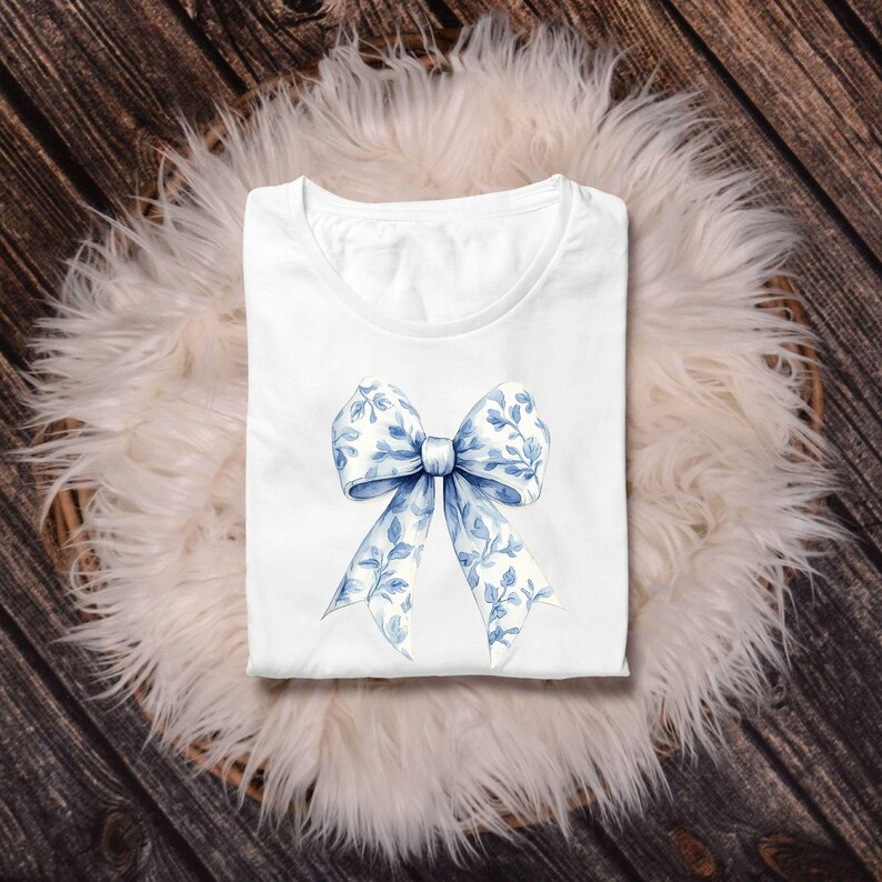 May include: White t-shirt with a blue and white floral bow design.