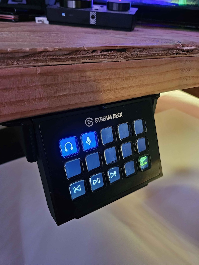 May include: A black Stream Deck with a variety of buttons, including a headphone icon, a microphone icon, and a play button. The buttons are illuminated with blue and green lights.