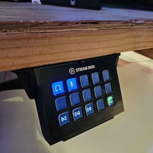 May include: A black Stream Deck with a blue lit headphone icon and a microphone icon. The deck has 15 buttons with various icons, including play, pause, and fast forward.