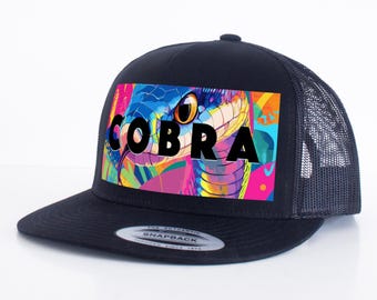 May include: Black trucker hat with a colorful graphic of a cobra with the word "COBRA" in black letters.