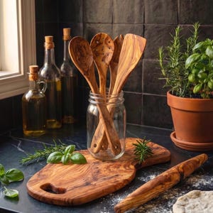 May include: A set of olive wood kitchen utensils including a slotted spoon, a solid spoon, and a flat spatula housed in a clear glass jar, accompanied by an olive wood cutting board and a matching rolling pin on a dark countertop.