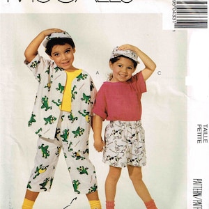 Peut inclure: Un patron de couture pour vêtements d'enfants. Le patron comprend deux modèles : une chemise blanche avec des grenouilles vertes et une chemise rose avec des chiens noirs et blancs. Le patron est pour les tailles petites.