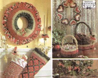 Peut inclure: Un livret de modèles de crochet avec des instructions pour réaliser une couronne de Noël, une chaussette, un panier et une jupe d'arbre. La couverture du livret présente un cœur rouge avec une étoile au centre et le mot "Crafts" en lettres rouges.