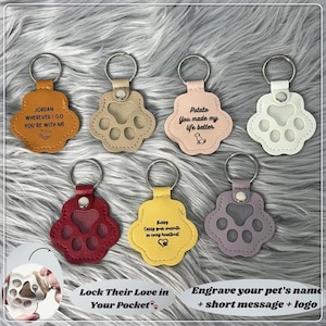 Peut inclure: Plusieurs porte-clés en forme de patte de chien, de couleurs variées, dont beige, rose, jaune, rouge et violet. Chaque porte-clé est orné d'un anneau métallique et d'un message personnalisé, comme "Jordan, où que j'aille, tu es avec moi."