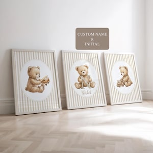May include: Three framed prints featuring watercolor illustrations of teddy bears. Each bear is depicted with a toy, including a plane, a letter, and a train. The prints have a striped background and are framed in white.