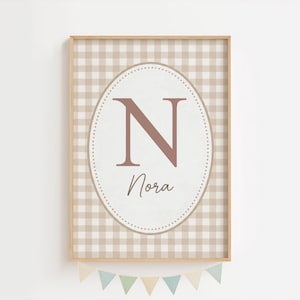 Peut inclure: Impression encadrée avec un motif vichy beige et blanc. Un ovale central affiche un "N" rose et le nom "Nora" en écriture cursive. Un cadre en bois et une guirlande de fanions sont en bas.