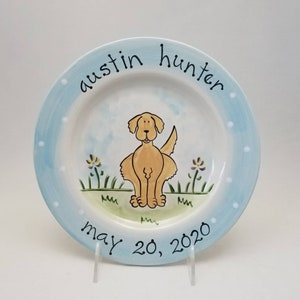 May include: A blue and white ceramic plate with a yellow dog illustration, the text "austin hunter may 20, 2020" and white polka dots around the edge.