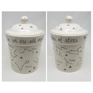 May include: White ceramic canister with a lid, featuring a black and white constellation design and the text "We are all made of stars".