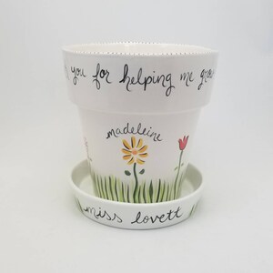 May include: White ceramic flower pot with a green and yellow flower design and the text "Thank you for helping me grow, madeleine miss lovett".