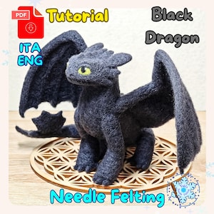 Può includere: Statuetta di drago nero fatta a mano con occhi gialli e grandi ali. Il drago è fatto di feltro e poggia su una base decorativa in legno. L'immagine include il testo "Tutorial", "Black Dragon" e "Needle Felting".