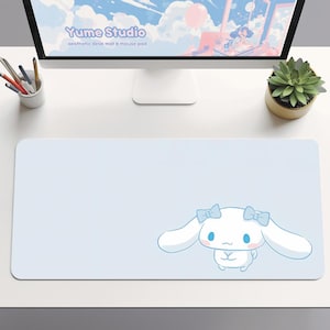May include: A pale blue desk mat featuring a cartoon character. The mat has a white cartoon character with long ears and blue bows. The text "Yume Studio aesthetic desk mat & mouse pad" is visible on the computer screen.