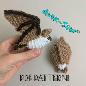 Pode incluir: Dois enfeites de morcego de crochê. Um morcego está em voo com asas marrons e marrom escuro, corpo branco e olhos pretos. O segundo morcego está dobrado com as asas fechadas. O texto "QUIK-SEW" e "PDF PATTERN!" também são visíveis.