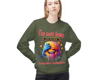 May include: An olive green sweatshirt with the text "I'm not lazy" above a colorful emoji covering its eyes. The emoji has a tongue sticking out and is surrounded by heart shapes. The text "I'm on power-saving mode" is below the emoji.