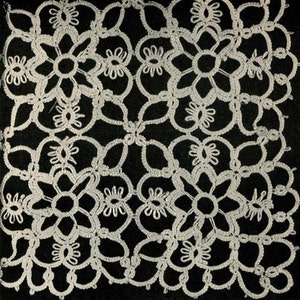 May include: A white crocheted lace doily with a floral pattern. The doily is made up of repeating flower shapes with small circles in the center of each flower.