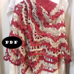 May include: A red and beige crocheted shawl with a scalloped edge. The shawl is draped over a white surface and has a PDF label.