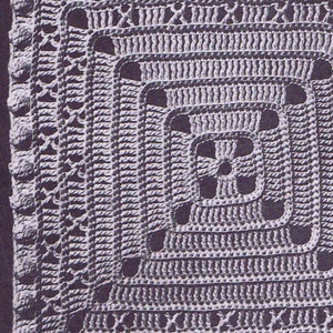 Puede incluir: Primer plano de un cuadrado tejido a crochet con un patrón texturizado. El cuadrado está hecho de hilo gris claro y tiene un borde de pequeños nudos redondos.