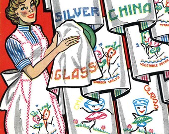 May include: A woman in a white and red striped apron is holding a white tea towel with the word "GLASS" embroidered on it. The tea towel is being used to cover a plate with a green design. There are several other tea towels in the background with different designs and embroidery, including "SILVER CHINA", "GARDEN WALTZ", "VEGETABLE POLKA", and "CHILI".
