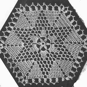 以下が含まれることがあります： 六角形の白いクロシェのドイリーで、詳細で複雑なデザインが施されています。ドイリーには中央に花のモチーフがあり、正方形の繰り返しパターンがあります。