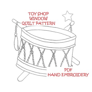 May include: A black and white line drawing of a toy drum with a star on top. The text "TOY SHOP WINDOW QUILT PATTERN" is above the drum and the text "PDF HAND EMBROIDERY" is below the drum.