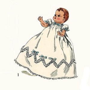 May include: A vintage illustration of a baby doll wearing a white christening gown with blue ribbon accents and lace trim.