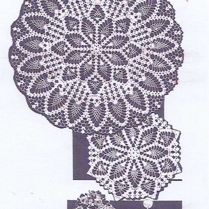 Op de afbeelding: Drie witte gehaakte doilies met een delicaat bloemenpatroon. De grootste doily is ongeveer 46 cm in diameter. De doilies worden getoond op een tafelsetting met een vaas met bloemen, bestek en glazen.