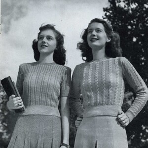 May include: Two women wearing knitted sweaters. The woman on the left is wearing a ribbed sweater with short sleeves and a skirt. The woman on the right is wearing a cable knit sweater with long sleeves and a skirt.