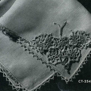 May include: A white linen handkerchief with a delicate crocheted lace border and a floral design in the corner. The design features three stylized flowers with a small bow in the center. The handkerchief is labeled "CT-254".