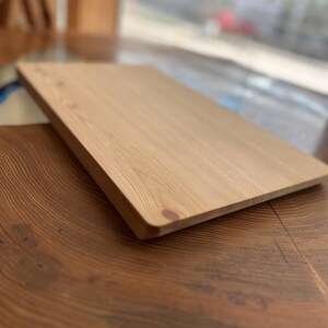 Op de afbeelding: Een lichtbruin houten snijplank met een glad oppervlak. De plank is gemaakt van natuurlijk hout en heeft een licht afgeronde rand.