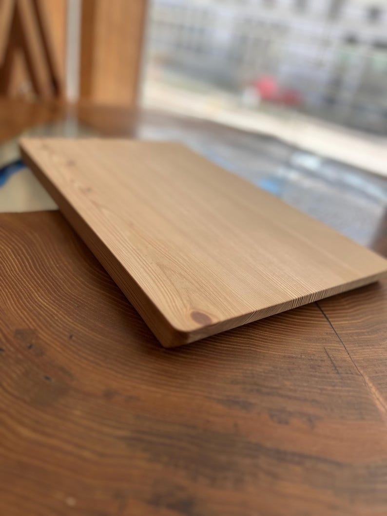 Op de afbeelding: Een lichtbruin houten snijplank met een glad oppervlak. De plank is gemaakt van natuurlijk hout en heeft een licht afgeronde rand.