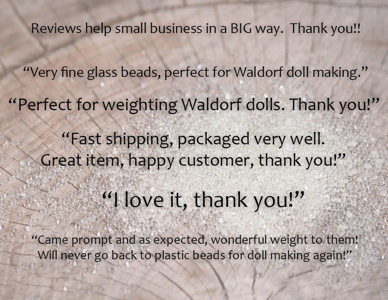 May include: Reviews on a wooden surface with the text "Reviews help small business in a BIG way. Thank you!!" and several customer reviews about glass beads, including "Very fine glass beads, perfect for Waldorf doll making.", "Perfect for weighting Waldorf dolls. Thank you!" and "I love it, thank you!"